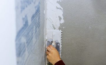 Handyman applying ceramic tiles on bathroom walls in bathroom during renovation