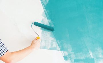 Home repair and improvement. Man coloring wall blue with a roller